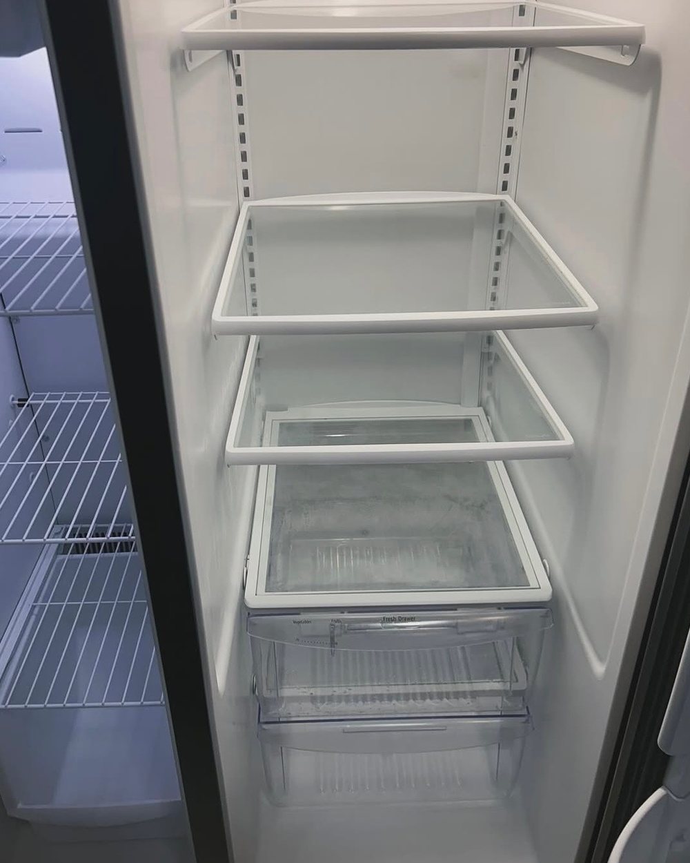 An emptied refrigerator cleaned shelf by shelf