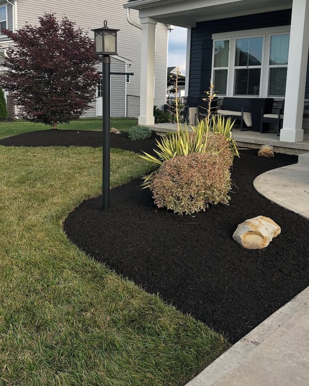 Fresh black mulch beds and edged lawn by BTI Clean